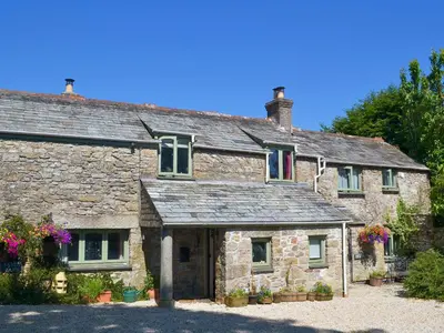 an old stone house with flowers in front of it at High View in Saint Breward