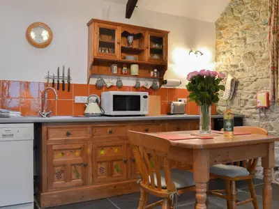 a kitchen with a wooden table with a microwave at Campion Cottage in Saint Teath