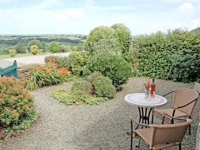 a patio with a table and chairs on a gravel yard at Campion Cottage in Saint Teath