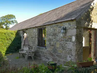 a stone cottage with a table and an umbrella at Campion Cottage in Saint Teath