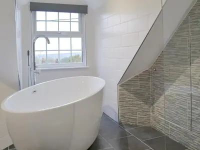 a white bathroom with a tub and a staircase at Gumburnville in Lanteglos