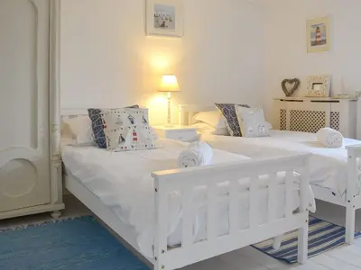 two beds in a room with white walls at Gumburnville in Lanteglos