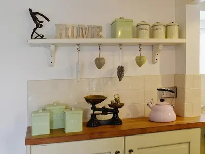 a kitchen with a counter top with a stove and shelves at Gumburnville in Lanteglos