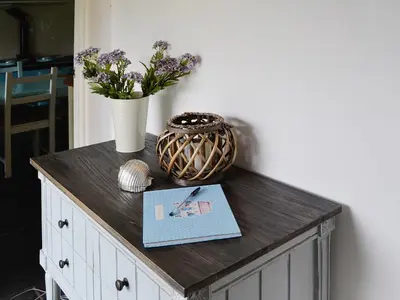 a table with a vase and a book and flowers at Gumburnville in Lanteglos