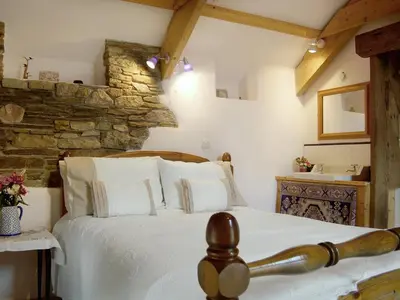 a bedroom with a bed and a stone wall at Well Barn in Lanteglos