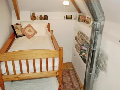 a small bedroom with a wooden bed in a attic at Well Barn in Lanteglos