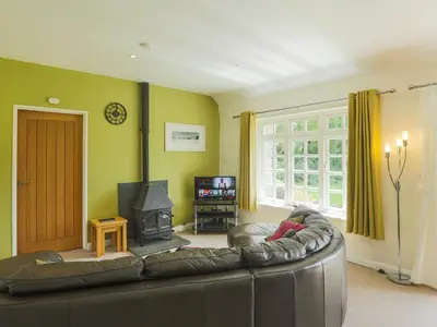 a living room with a leather couch and a fireplace at Drovers in Lanteglos