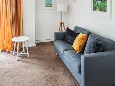 a living room with a blue couch and a table at Valley Truckle Bungalow in Camelford
