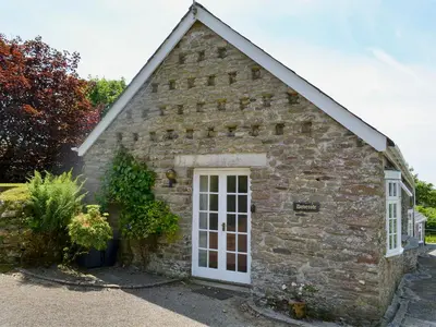 a small stone building with a white door at Dovecote-Tnq in Camelford