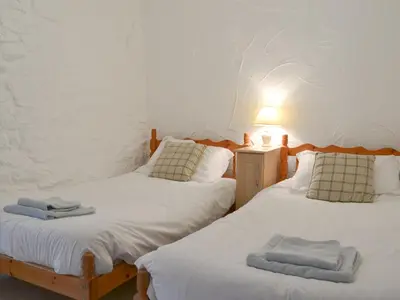 two beds in a room with a lamp and towels on them at Dovecote-Tnq in Camelford