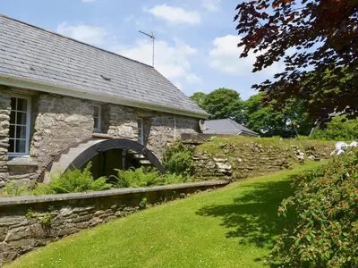an old stone house with a stone wall and a yard at Dovecote-Tnq in Camelford