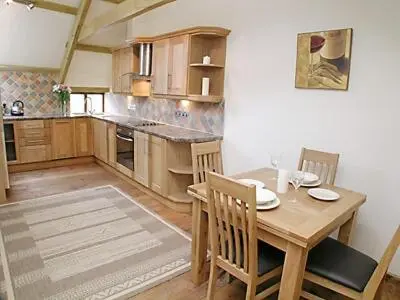a kitchen with a wooden table and chairs in a room at The Stable in North Petherwin