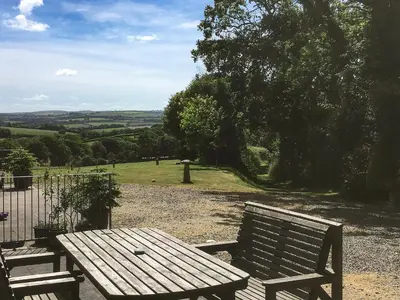 a wooden bench sitting in front of a field at The Stable in North Petherwin