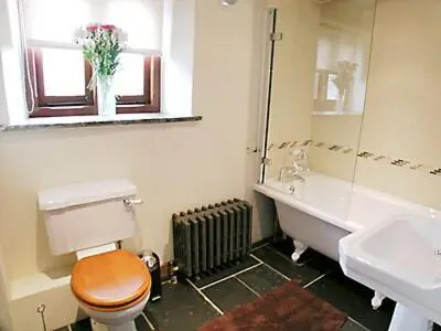 a bathroom with a toilet and a tub and a sink at The Stable in North Petherwin