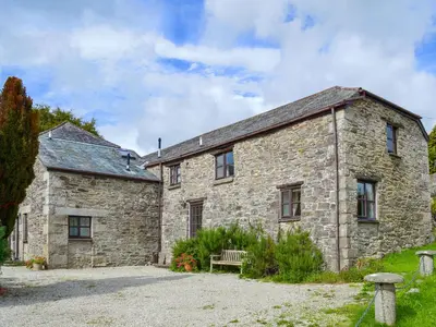 an old stone building with a bench in front of it at Stable End in Trewen