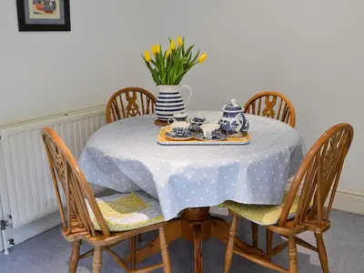 a dining room table with a blue and white table cloth at Stable End in Trewen