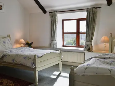 a bedroom with two beds and a window at Stable End in Trewen
