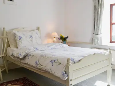 a bedroom with a white bed with blue flowers at Stable End in Trewen
