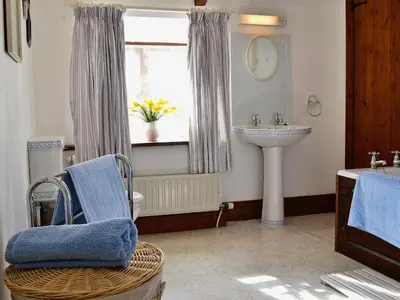 a bathroom with a sink and a toilet and a window at Stable End in Trewen