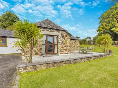a stone cottage with a patio and palm trees at Kettle's On - Tkc in Tresmeer
