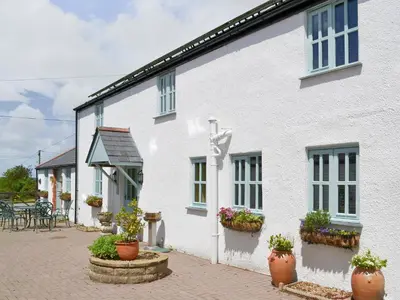 a white house with potted plants in front of it at Barfield's Cherry Tree Cottage in Warbstow