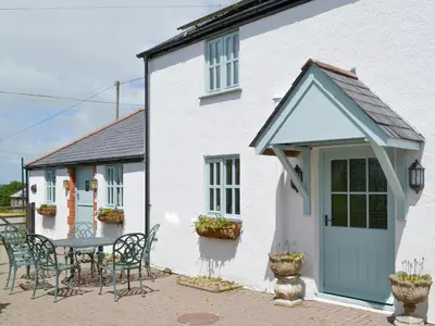 a white house with a table and chairs in front of it at Barfield's Cherry Tree Cottage in Warbstow