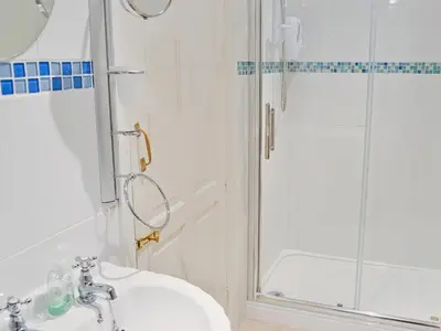 a white bathroom with a shower and a sink at Barfield's Cherry Tree Cottage in Warbstow
