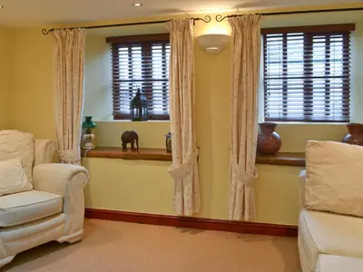a living room with a chair and two windows at Barfield's Cherry Tree Cottage in Warbstow