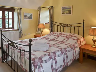 a bedroom with a bed and two tables and two lamps at Barfield's Cherry Tree Cottage in Warbstow