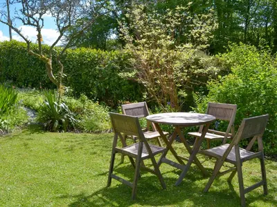 three chairs and a table in the grass at The Thatch Cottage in South Petherwin