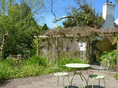 a table and two chairs in a garden at The Thatch Cottage in South Petherwin