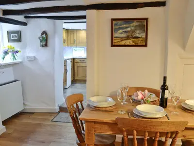 a kitchen and dining room with a wooden table and chairs at The Thatch Cottage in South Petherwin
