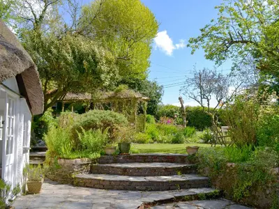 a garden with stairs leading to a house at The Thatch Cottage in South Petherwin