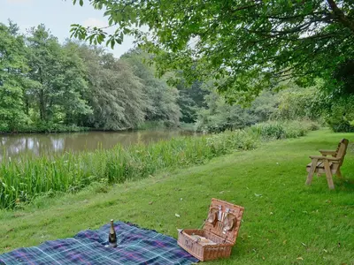 a picnic blanket on the grass next to a river at The Granary in Egloskerry