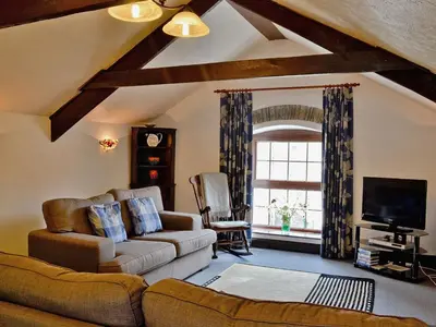 a living room with a couch and a tv at The Granary in Egloskerry