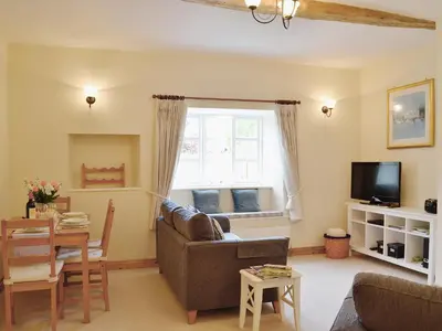 a living room with a couch and a table and a window at Barton Cottage in North Petherwin