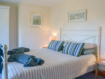 a bed with blue and white sheets and pillows at Barton Cottage in North Petherwin