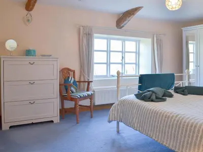a bedroom with a bed and a dresser and a window at Barton Cottage in North Petherwin