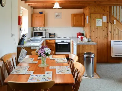 a kitchen with a wooden table with flowers on it at Merlin View in Saint Mawgan
