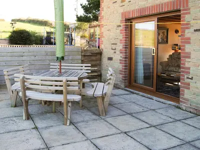 a wooden table and chairs on a patio at Merlin View in Saint Mawgan