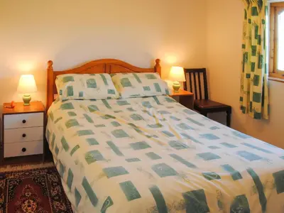 a bedroom with a bed and two lamps and a window at Porth View in Saint Mawgan