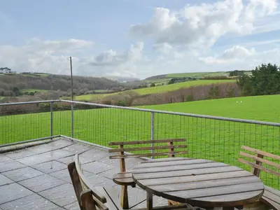 a wooden table and chairs on a patio with a view at Porth View in Saint Mawgan