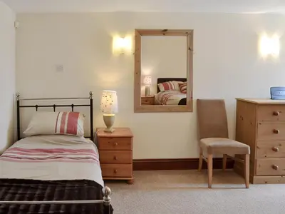 a bedroom with a bed and a mirror and a chair at Trescowthick Barn in Zelah
