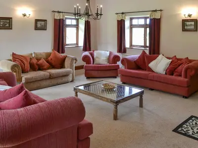 a living room with red couches and a coffee table at Trescowthick Barn in Zelah