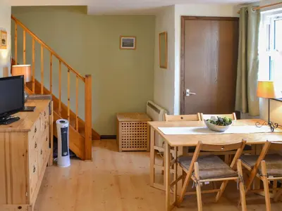 a living room with a wooden table and a television at Willow Cottage in Newlyn East