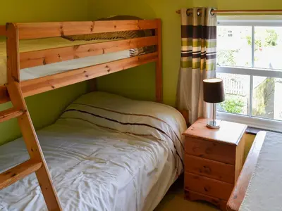 a bedroom with two bunk beds and a table with a lamp at Willow Cottage in Newlyn East