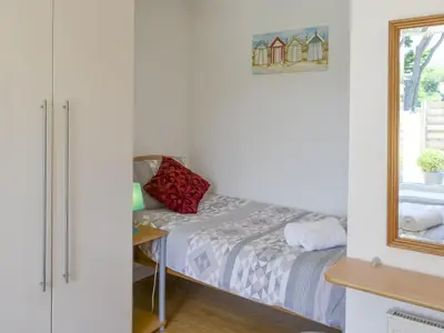 a small bedroom with a bed and a mirror at Palm Villa in Saint Columb Minor