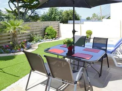 a table and chairs with an umbrella in a garden at Palm Villa in Saint Columb Minor