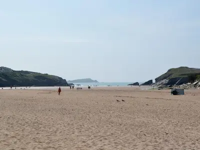 a group of people walking on a sandy beach at Palm Villa in Saint Columb Minor