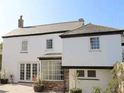 a white house with plants in front of it at Manor Cottage in Crantock